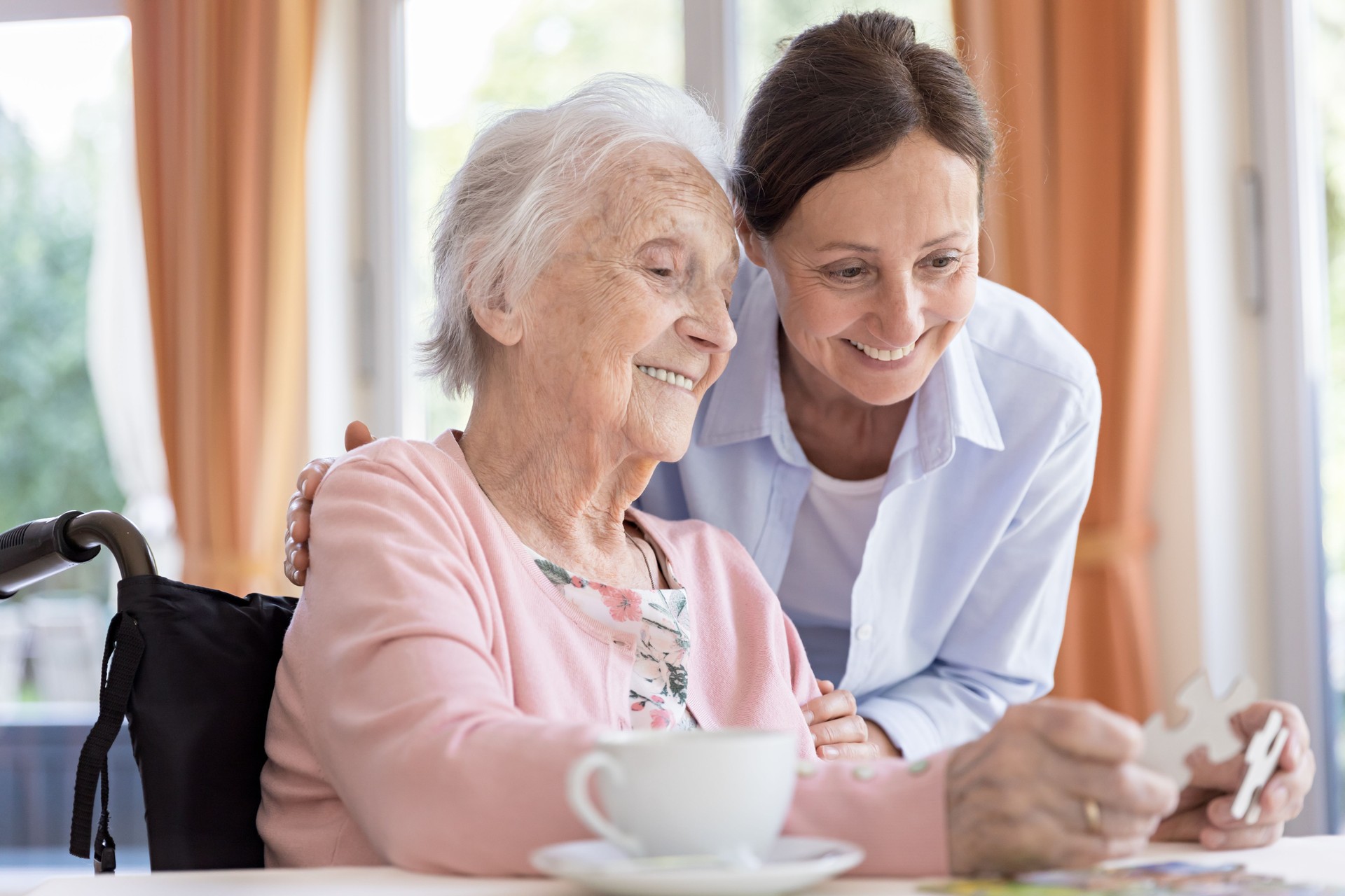 Happy senior woman in wheelchair with caregiver