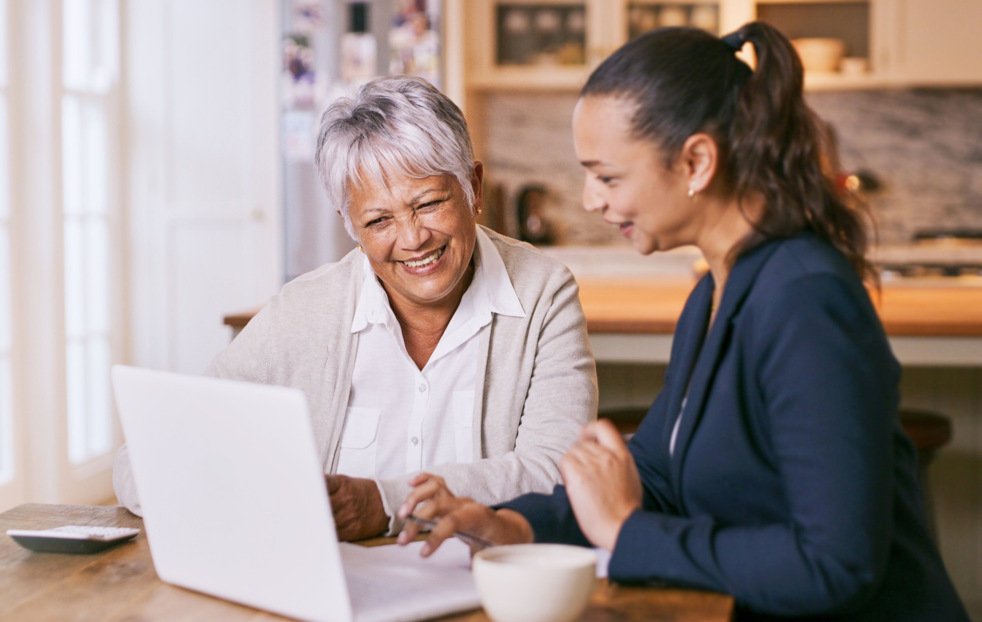 Shot of a senior woman using a laptop during a meeting with a consultant at home