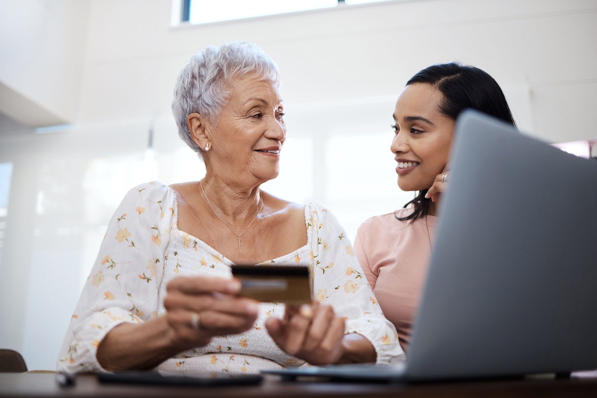 Shot of a senior woman using a laptop and credit card with her daughter at home